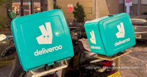 Deliveroo scooters with insulated food delivery boxes parked in Cardiff, symbolising the modern gig economy.