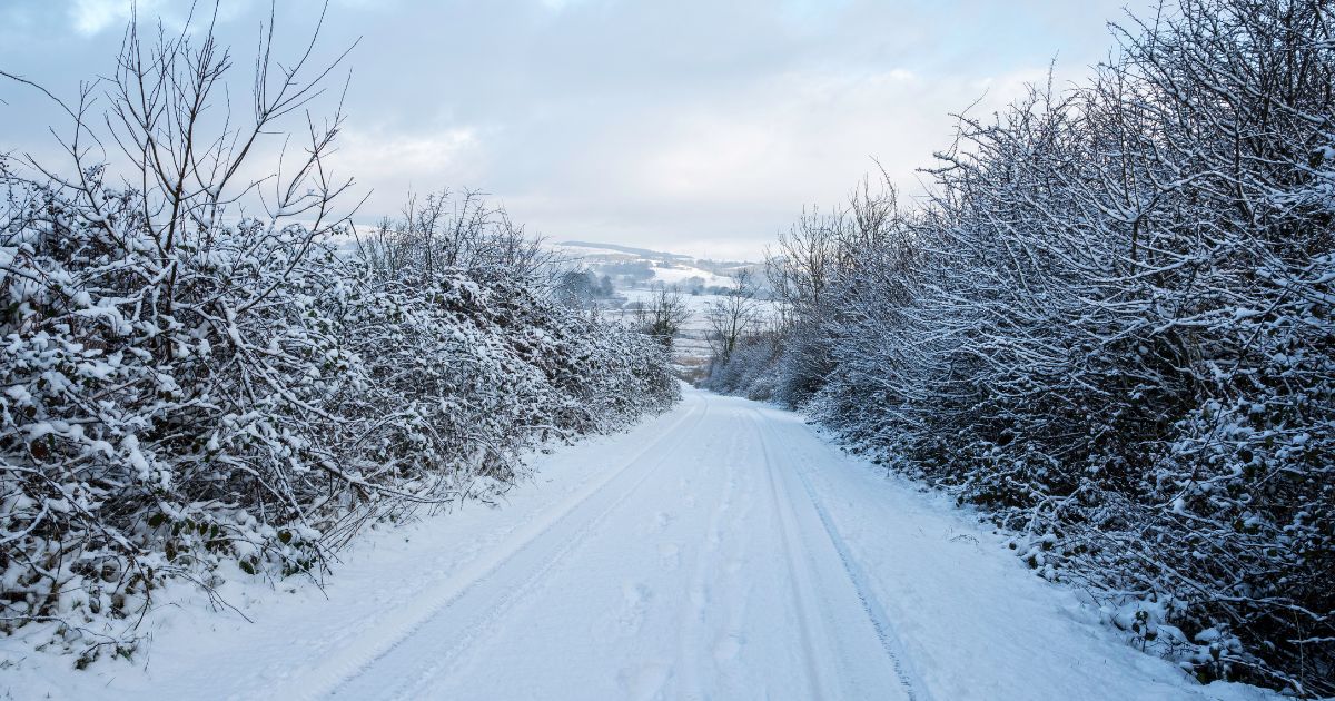 Snow-covered country road after a heavy snowfall in South Wales, UK, showcasing a serene winter landscape.