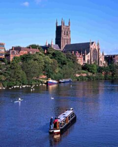 Worcester Cathedral towering above the River Severn, with leisure boats and rowers enjoying the serene waters.