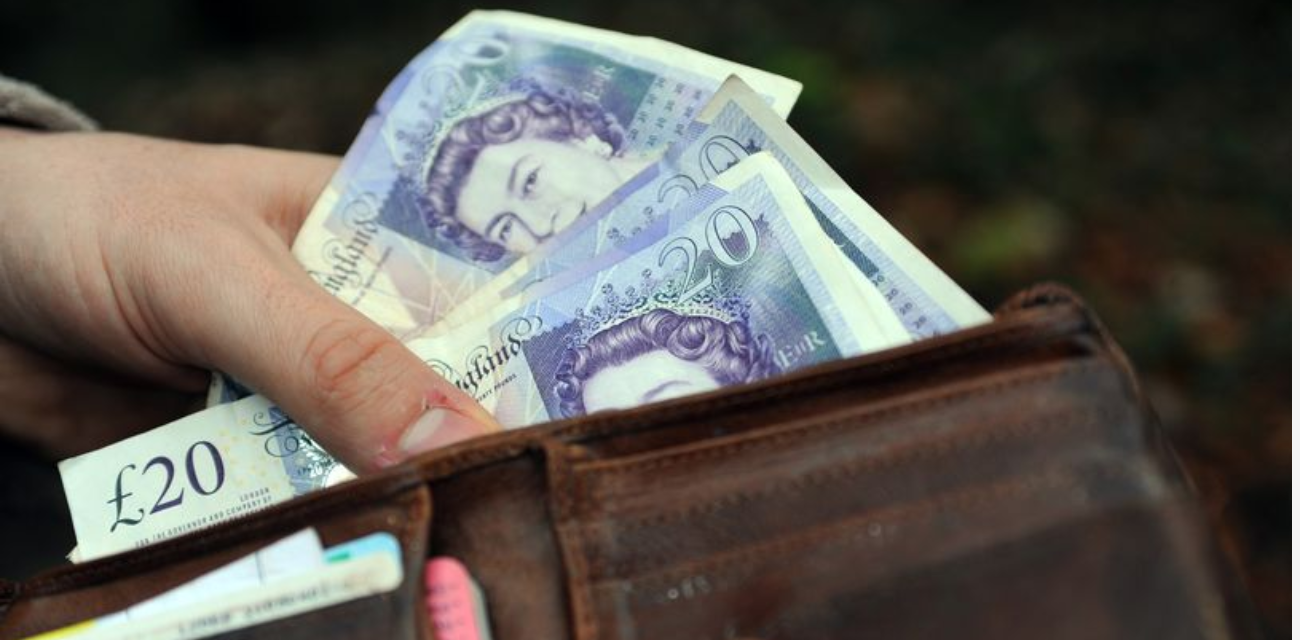 A hand holding a wallet filled with £20 notes, representing the wage increase for UK workers.