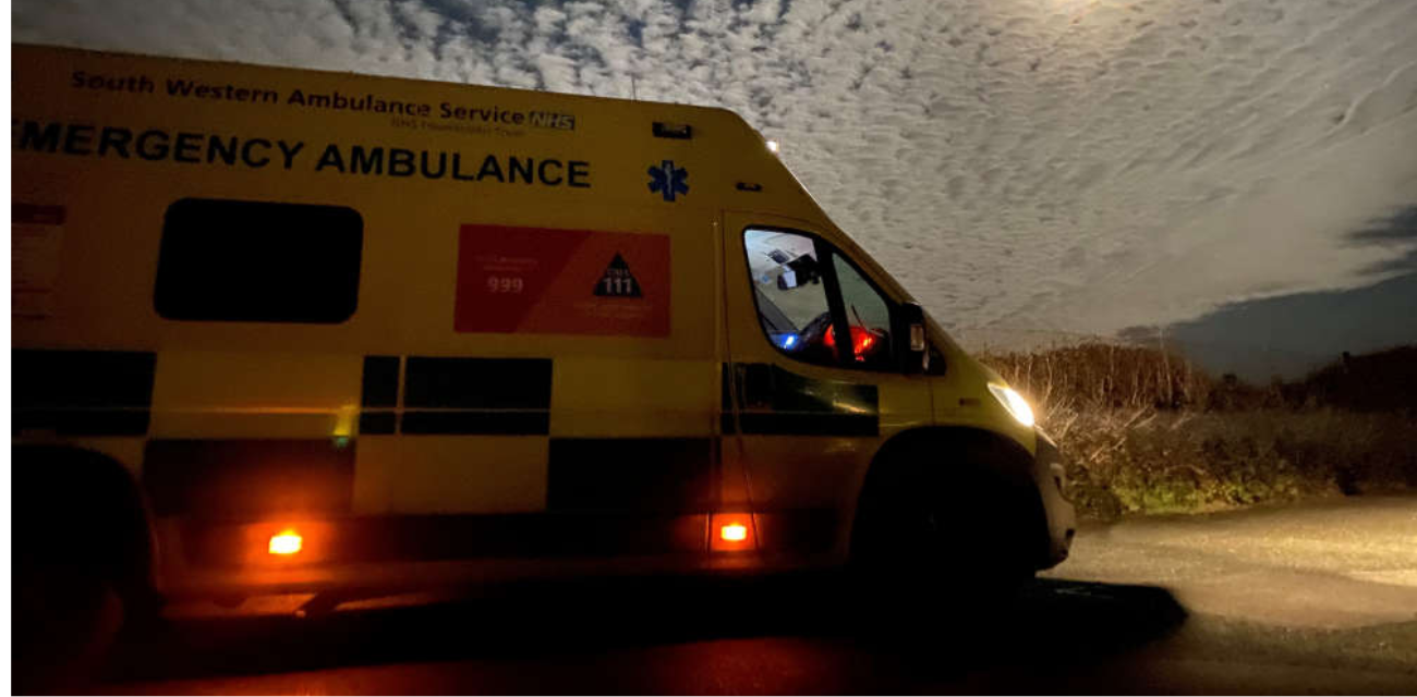 "South Western Ambulance Service NHS emergency ambulance parked at night with lights on under a cloudy sky, highlighting Halloween safety awareness."