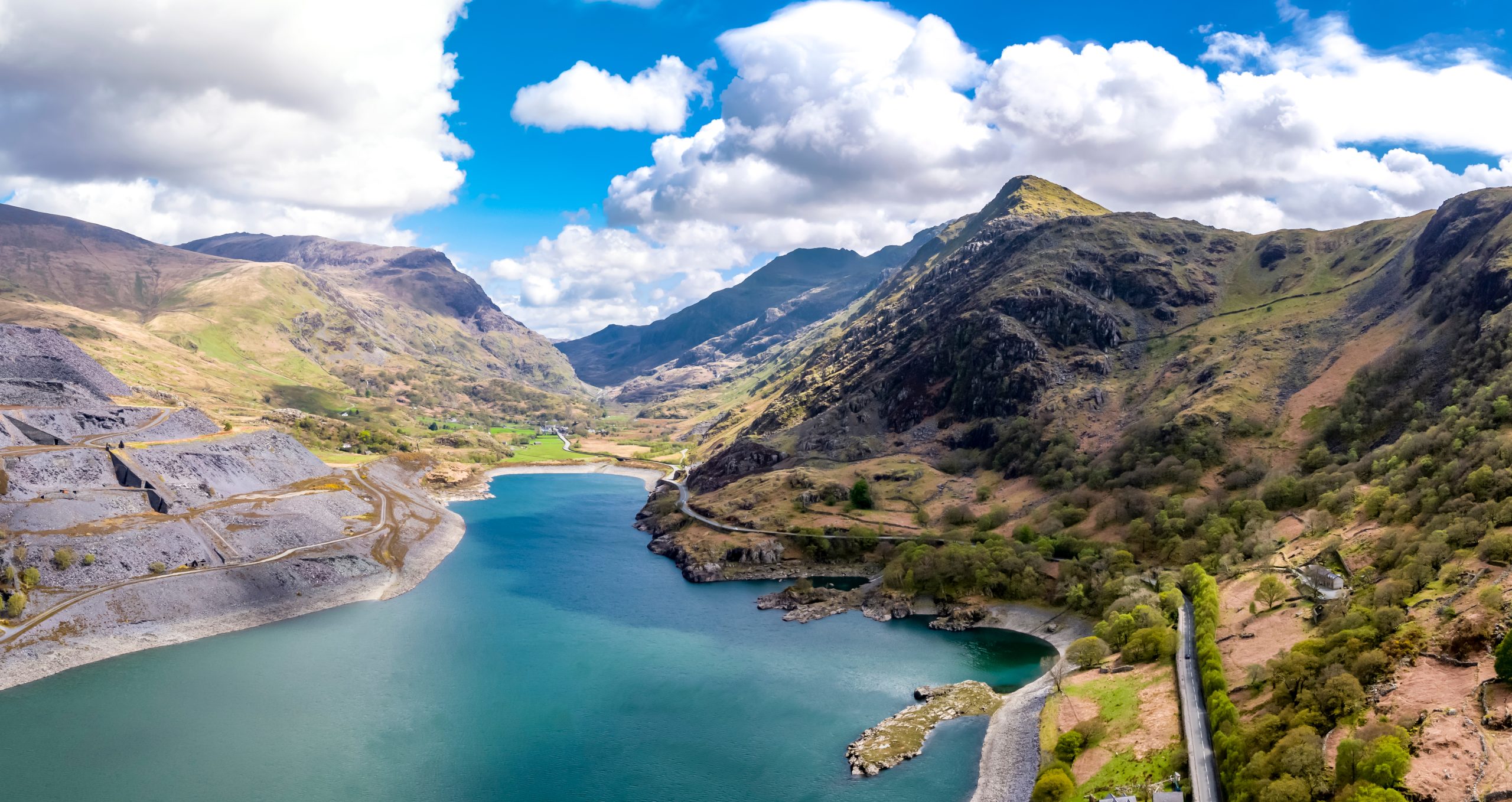 Aerial view of Snowdonia National Park near Dolbadarn Castle in Llanberis, featuring mountains, lake, and lush valley.