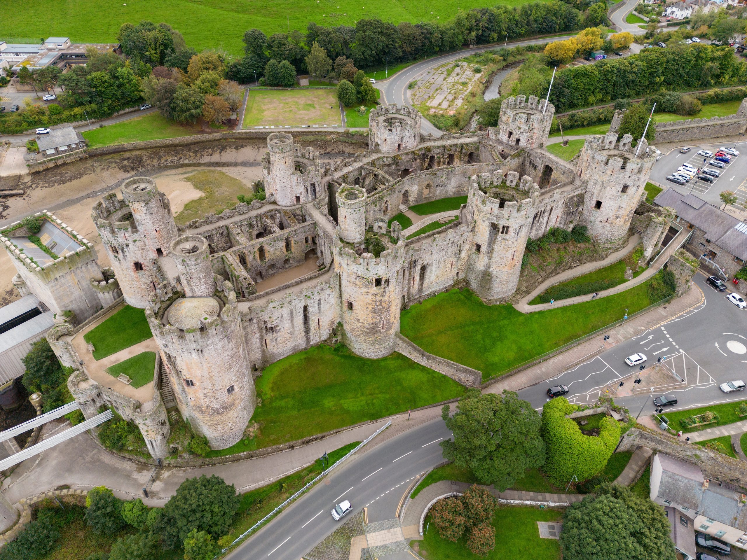 Aerial view of Conwy Castle in North Wales, a large medieval fortress surrounded by towers, stone walls, and the historic town of Conwy.