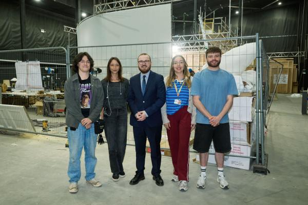 Skills and Culture Minister Jack Sargeant stands with trainees Charlie, Jacob, Rosie, and Robyn on the Cardiff set of Industry Season 4, showcasing Welsh Government support for TV production training.
