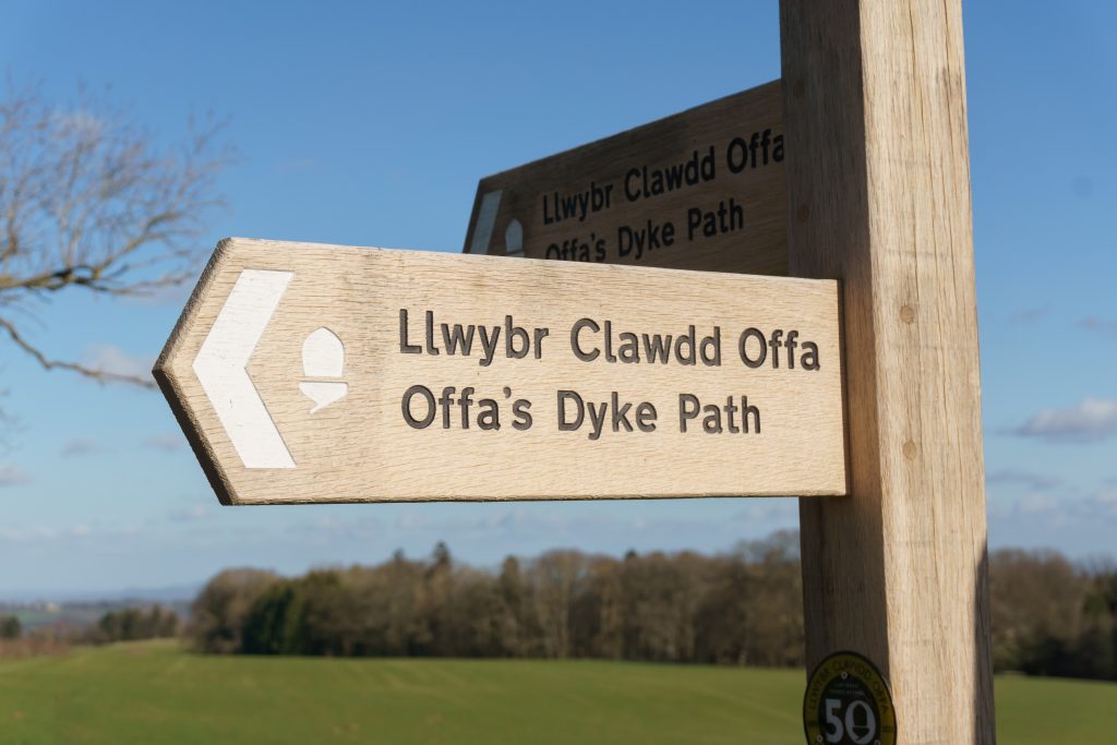 Wooden signpost marking Offa’s Dyke Path, the ancient boundary line between Wales and England.
