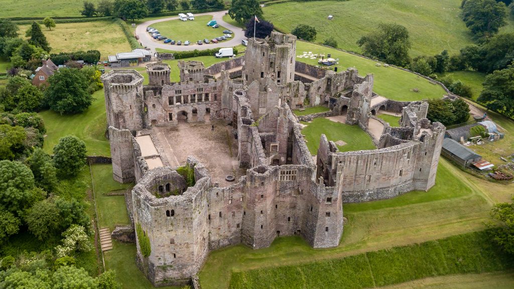 Aerial view of Raglan Castle ruins in South Wales, surrounded by green fields