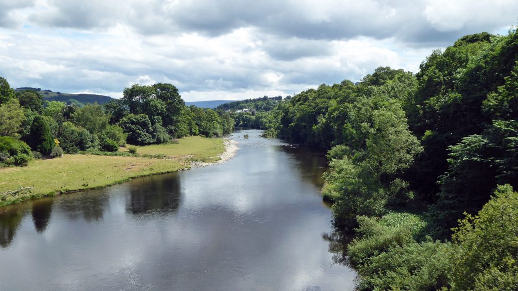 River Wye flowing through a lush valley, marking the historic border between Wales and England.