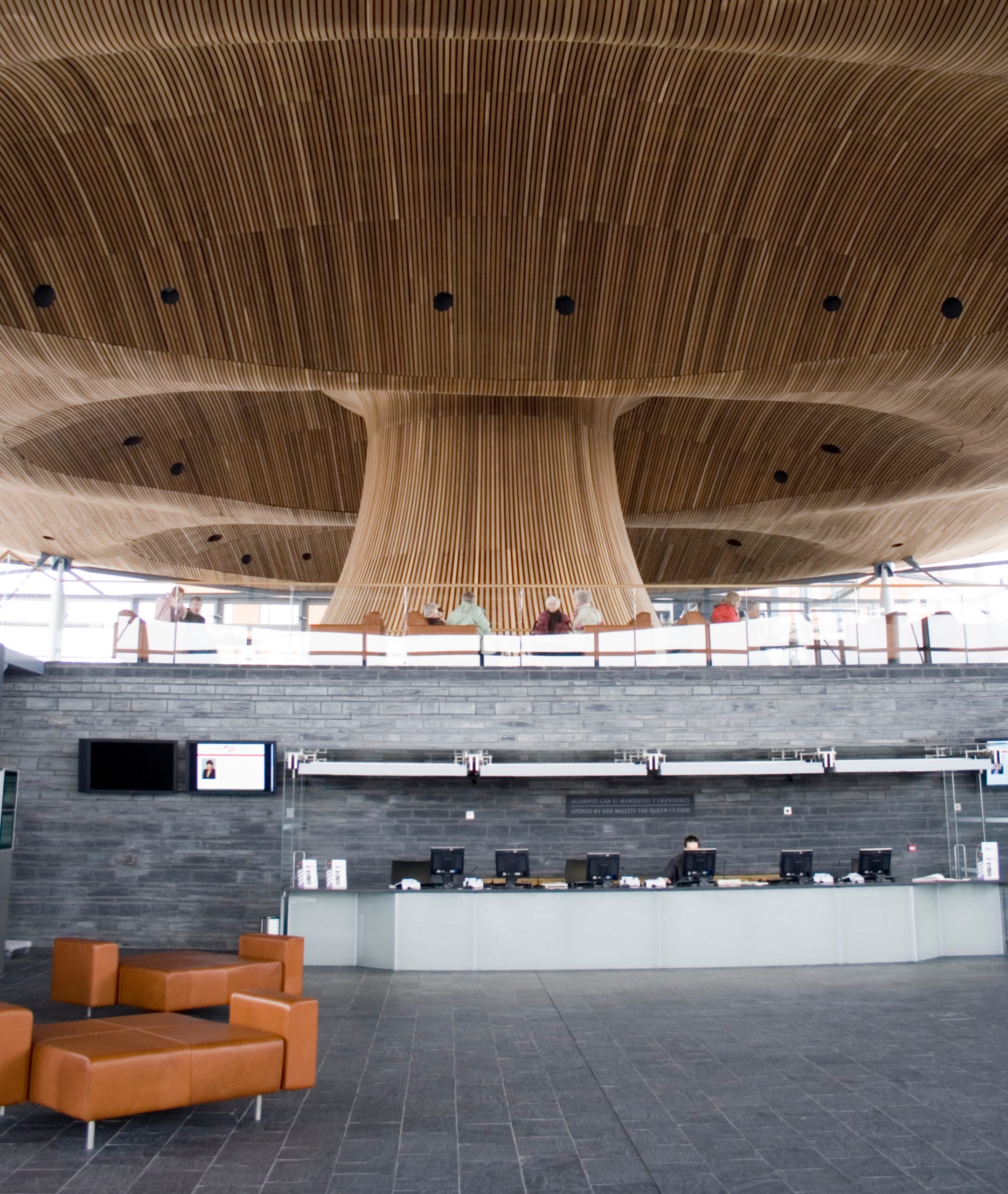 Interior view of the Senedd building in Cardiff, showcasing its unique wooden ceiling and public reception area.
