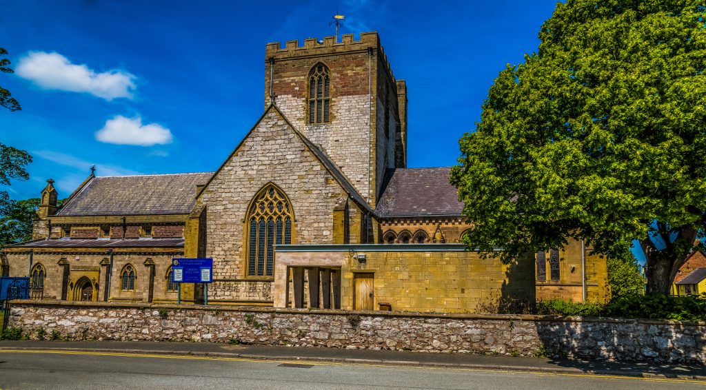 Exterior view of St Asaph Cathedral in North Wales, a historic church surrounded by stone walls and greenery.