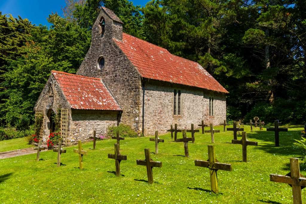 Ancient stone church of St Davids on Caldey Island with wooden grave markers in South Wales